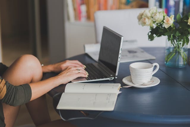 person doing research on a computer and notebook