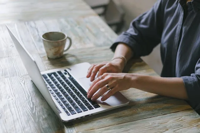 Person working on a laptop with a coffee